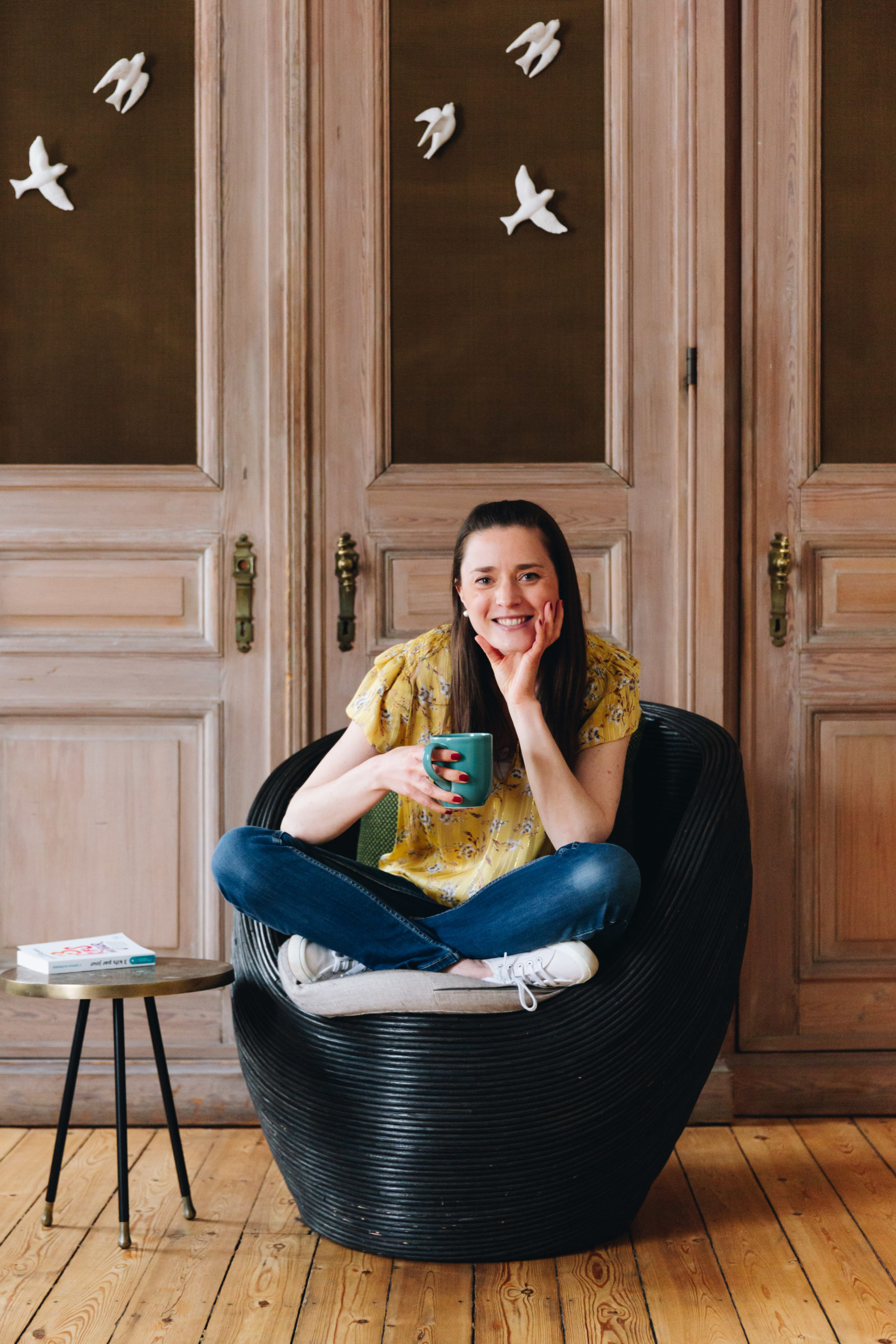 femme assise avec un tee-shirt jaune avec une tasse en main souriante
